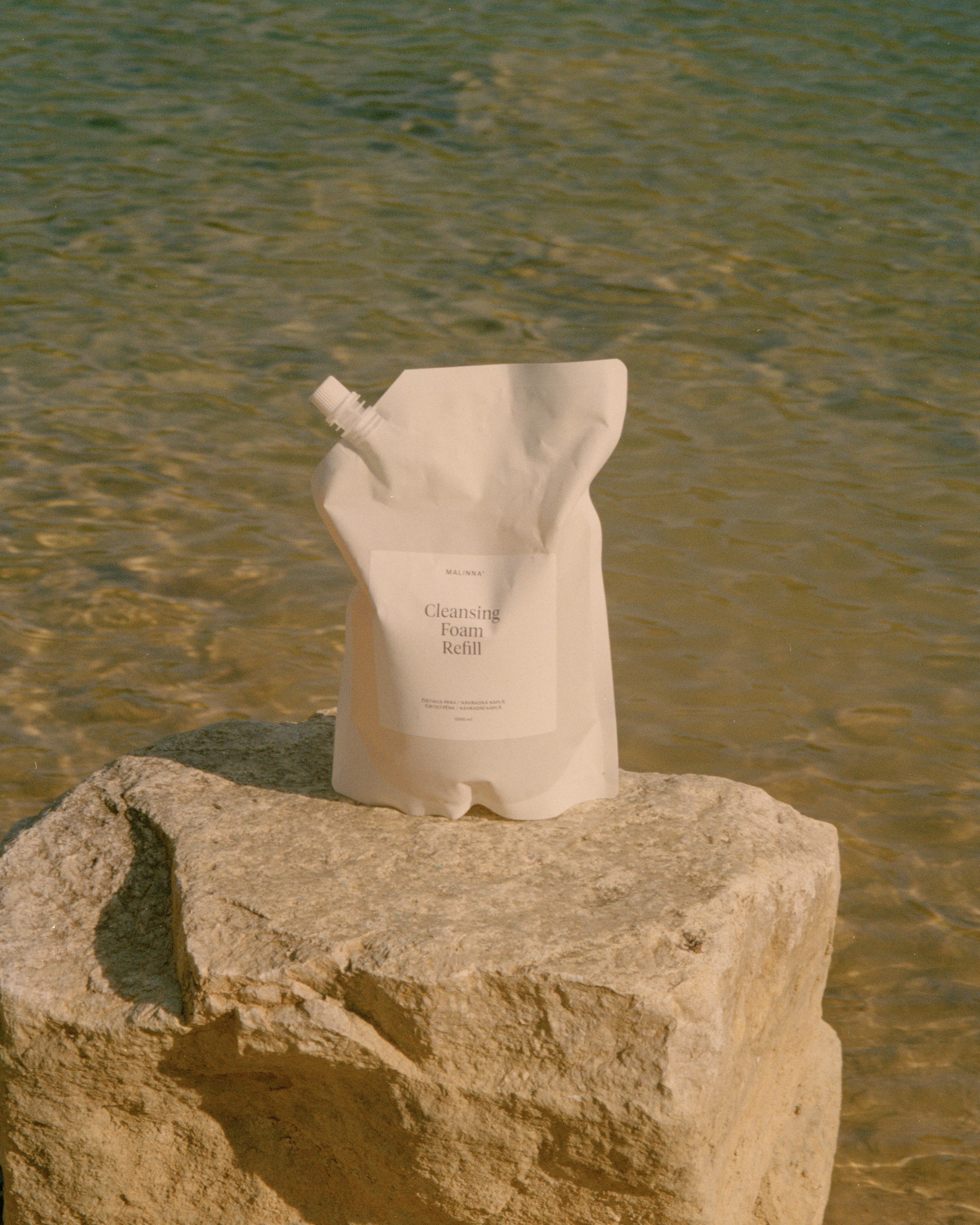 MALINNA Cleansing Foam refill na kameni v pozadi s vodou