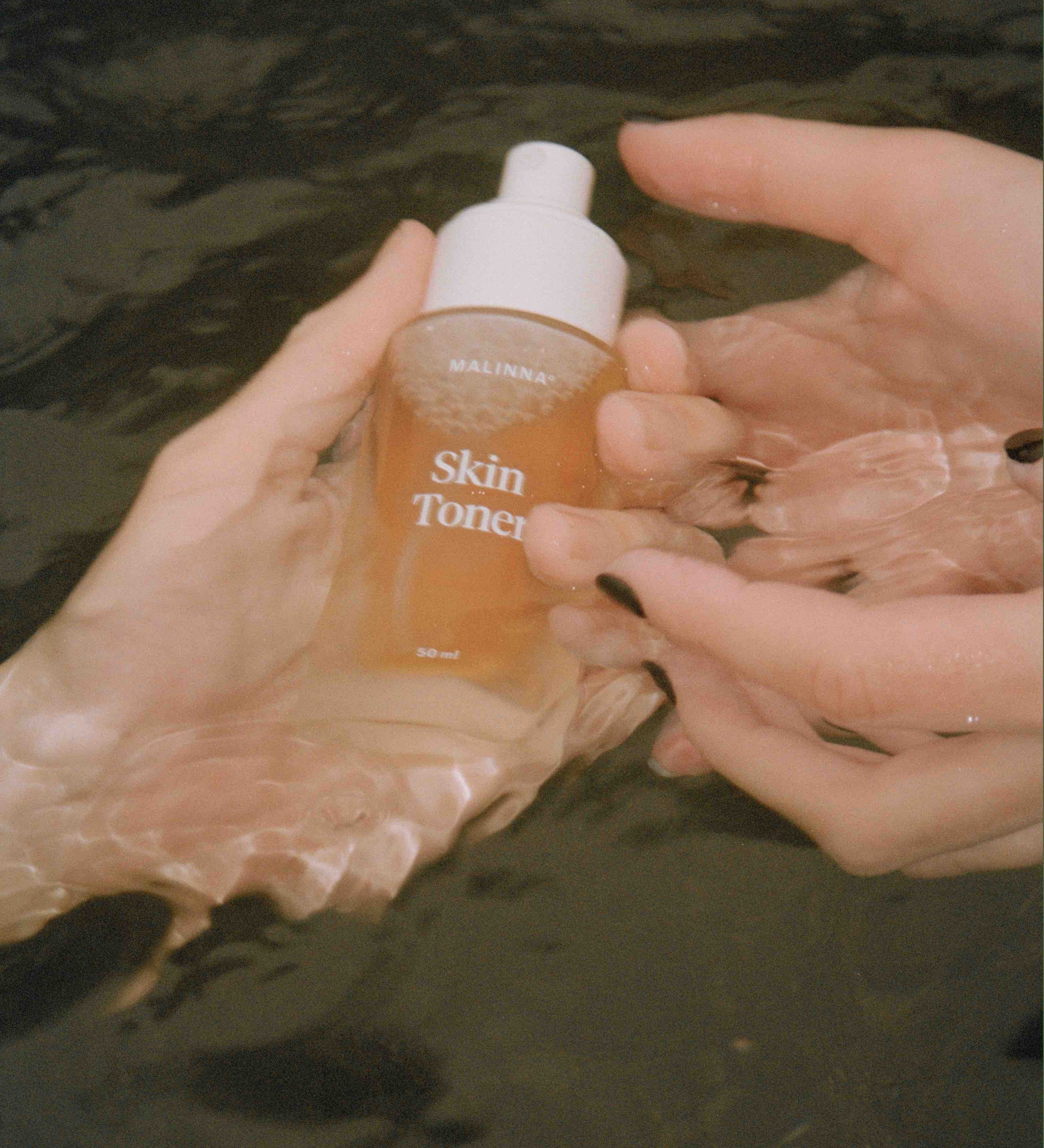 MALINNA Skin Toner v skle držaný v rukách ponorených vo vode