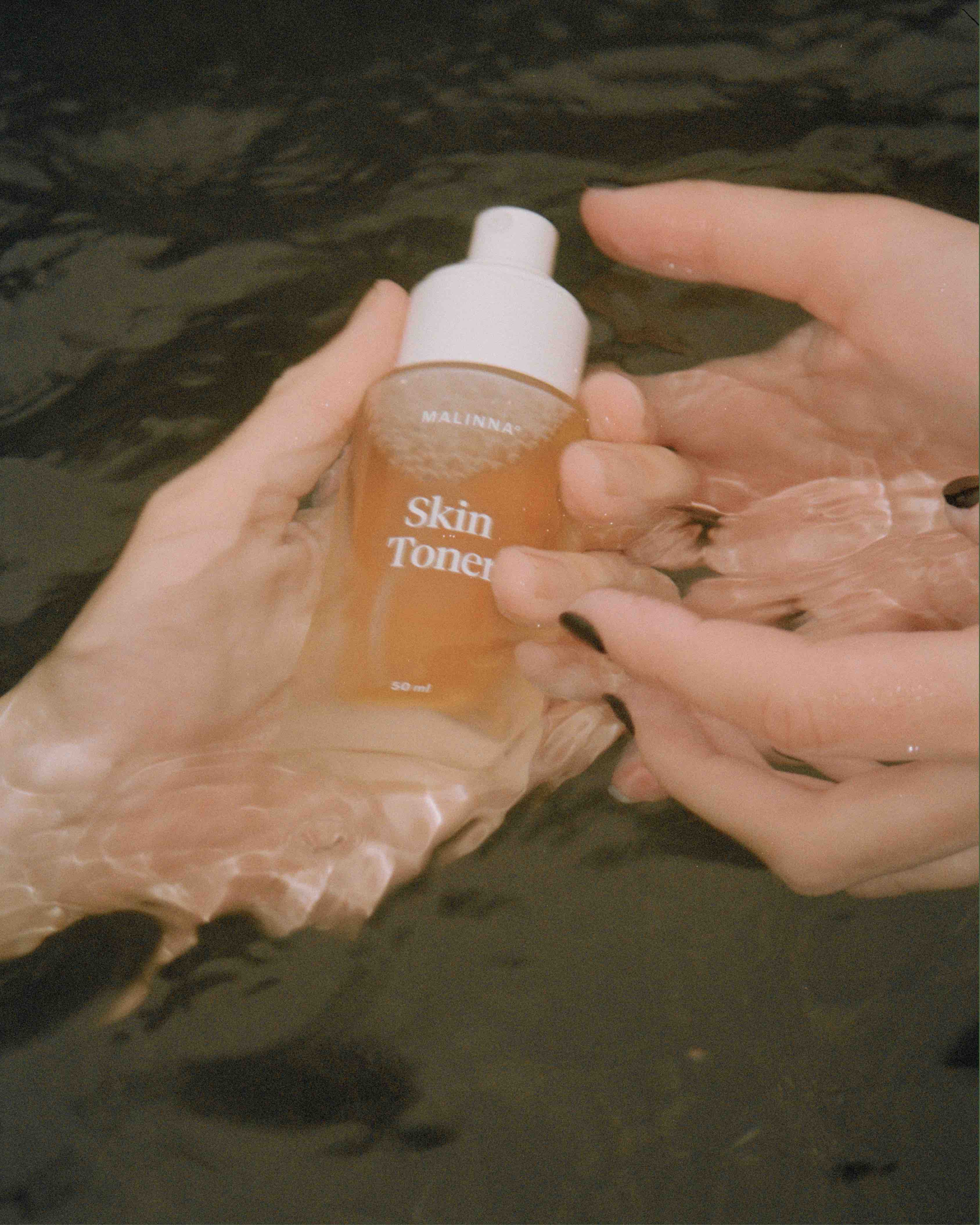 MALINNA Skin Toner v skle držaný v rukách ponorených vo vode
