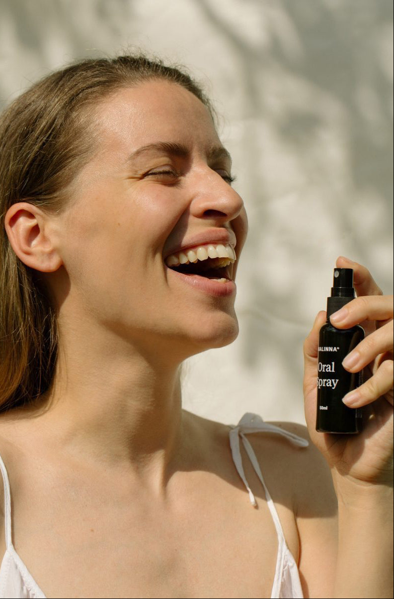 Smejúca sa žena drží v ruke MALINNA Oral spray