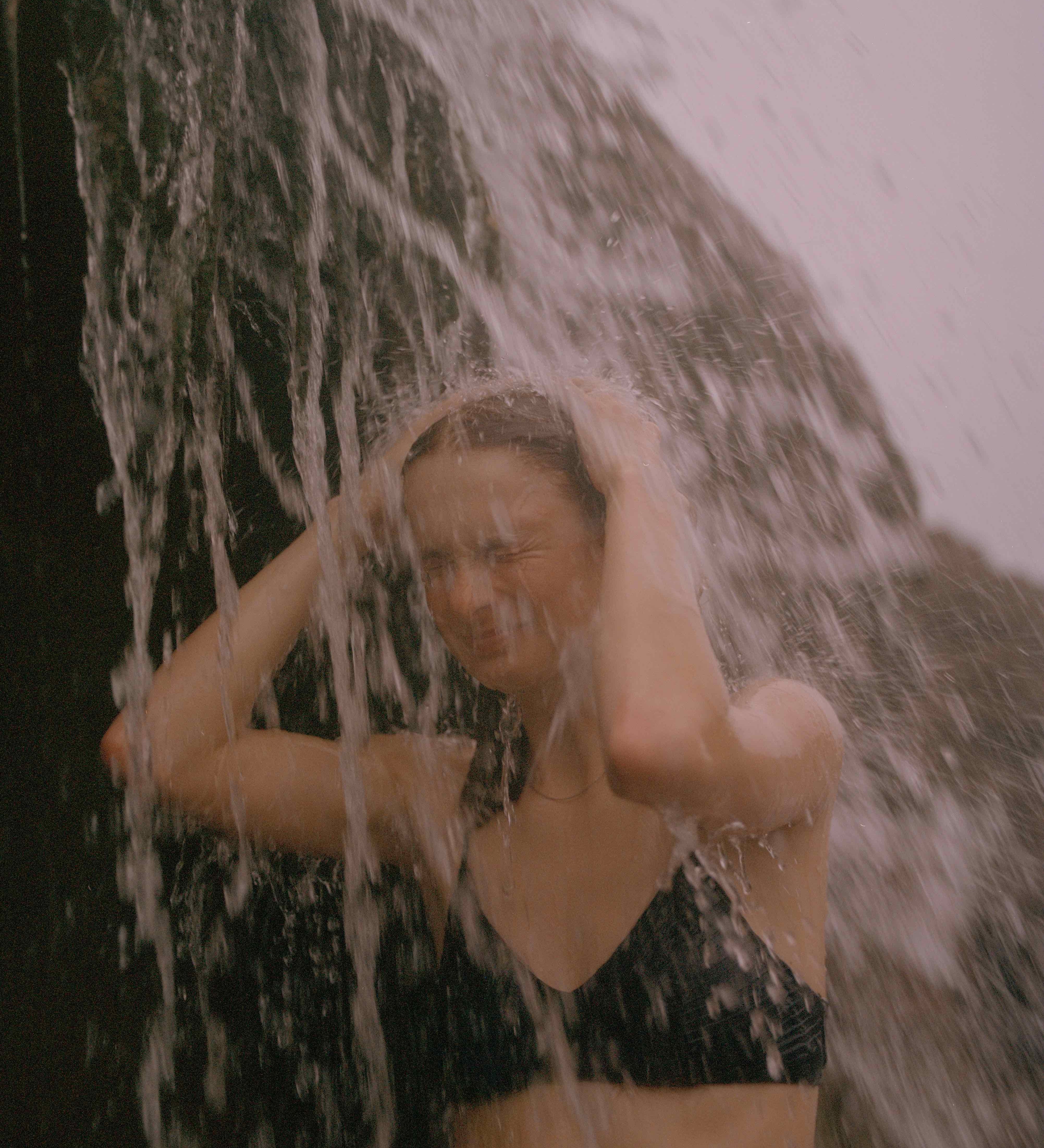 Žena stojaca pod vodopádom