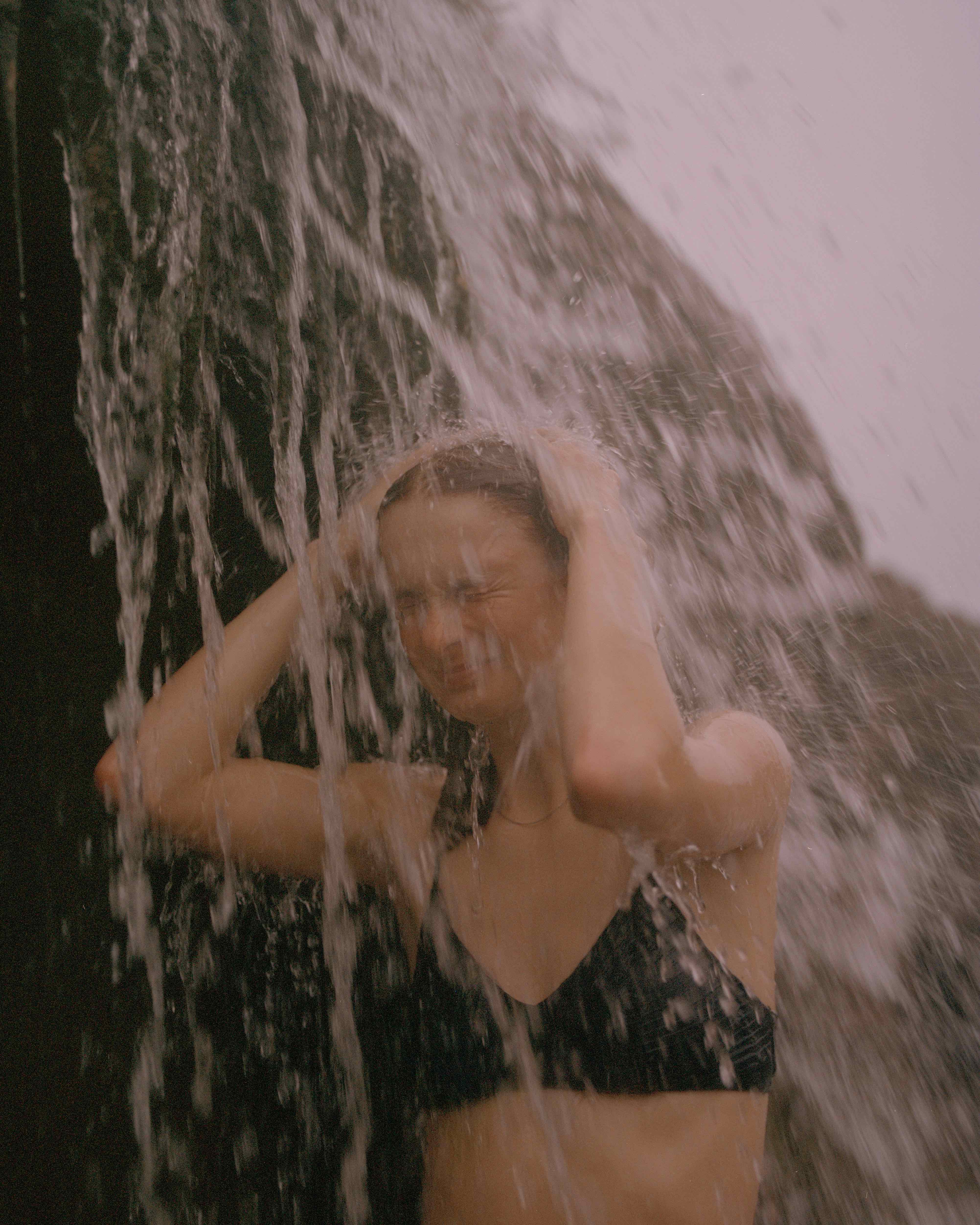 Žena stojaca pod vodopádom