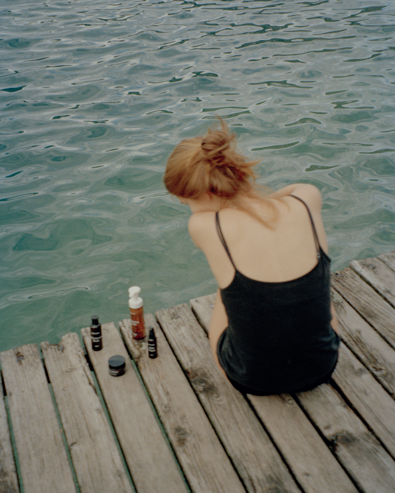 Žena sedí pri vode a vedľa nej má MALINNA produkty